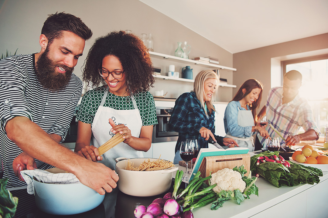 Gruppe junger, froehlicher Menschen beim kochen
